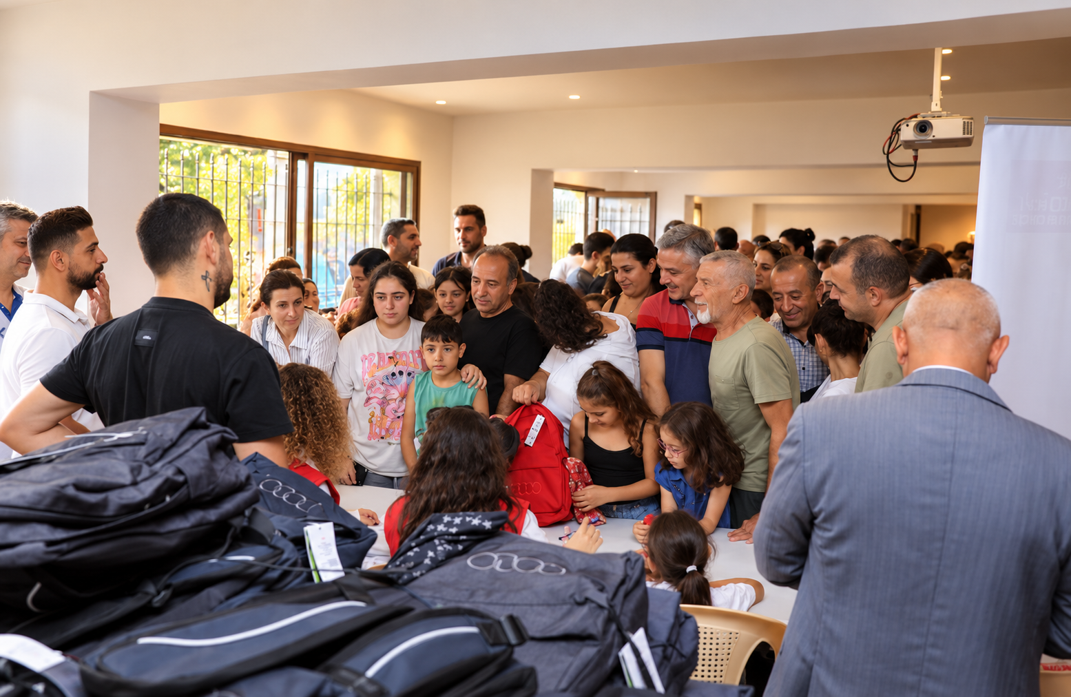Adults and children gather at a community event in Lebanon to receive school backpacks and support from volunteers.